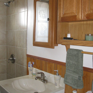 Immagine di una piccola stanza da bagno con doccia american style con ante con bugna sagomata, ante beige, top in superficie solida, piastrelle beige, piastrelle in gres porcellanato, vasca ad alcova, vasca/doccia, WC a due pezzi, lavabo integrato, pareti bianche e pavimento in gres porcellanato