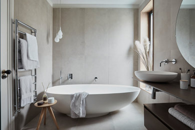 Inspiration for a large contemporary ensuite bathroom in London with a freestanding bath, beige tiles, porcelain tiles, porcelain flooring, a vessel sink, beige floors, brown worktops and flat-panel cabinets.