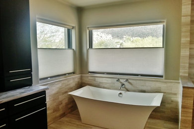 Imagen de cuarto de baño moderno con puertas de armario negras, encimera de mármol, bañera exenta, baldosas y/o azulejos multicolor, paredes multicolor y suelo de mármol