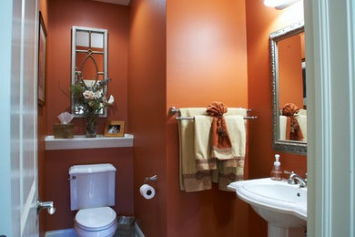 Bathroom - mid-sized traditional 3/4 ceramic tile bathroom idea in Columbus with a two-piece toilet, orange walls, a pedestal sink and solid surface countertops