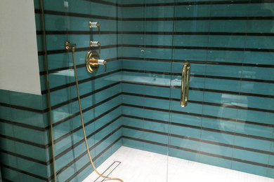 Modelo de cuarto de baño principal retro de tamaño medio con ducha empotrada, sanitario de una pieza, baldosas y/o azulejos azules, baldosas y/o azulejos de vidrio, paredes blancas, lavabo integrado y ducha con puerta con bisagras