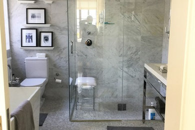 ニューヨークにある高級な中くらいなコンテンポラリースタイルのおしゃれなマスターバスルーム (オープンシェルフ、白いキャビネット、置き型浴槽、コーナー設置型シャワー、一体型トイレ	、グレーのタイル、大理石タイル、グレーの壁、大理石の床、ペデスタルシンク、グレーの床、開き戸のシャワー) の写真