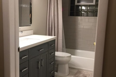 Example of a mid-sized classic 3/4 gray tile and subway tile porcelain tile bathroom design in Chicago with shaker cabinets, gray cabinets, a two-piece toilet, gray walls, an undermount sink and solid surface countertops