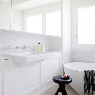 Inspiration for a contemporary bathroom in Sydney with shaker cabinets, white cabinets, a freestanding tub, gray tile, white tile, mosaic tile, white walls, a wall-mount sink and beige floor.
