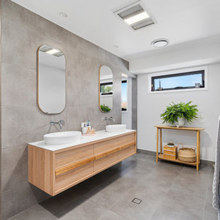 Photo of a large contemporary master bathroom in Gold Coast - Tweed with flat-panel cabinets, light wood cabinets, an alcove shower, gray tile, porcelain tile, grey walls, porcelain floors, a vessel sink, solid surface benchtops, grey floor, an open shower and white benchtops.