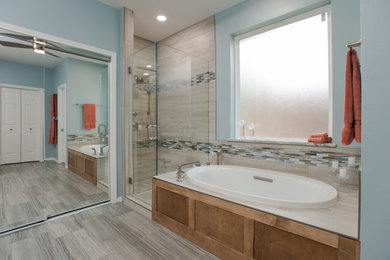 Inspiration for a mid-sized transitional master brown tile and porcelain tile porcelain tile and gray floor bathroom remodel in Dallas with shaker cabinets, medium tone wood cabinets, blue walls, an undermount sink, granite countertops, a hinged shower door and multicolored countertops