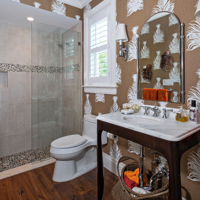 Inspiration for a tropical 3/4 beige tile dark wood floor and brown floor alcove shower remodel in Miami with open cabinets, a two-piece toilet, brown walls, a console sink and white countertops