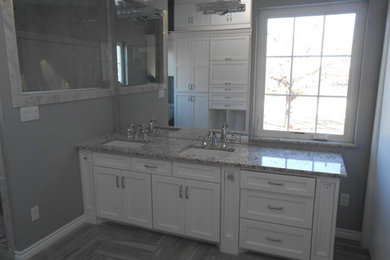 Imagen de cuarto de baño principal minimalista con sanitario de una pieza, paredes grises, suelo de travertino, lavabo bajoencimera, encimera de granito, armarios con paneles con relieve y puertas de armario blancas