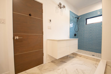 ニューヨークにあるお手頃価格の中くらいなコンテンポラリースタイルのおしゃれなバスルーム (浴槽なし) (フラットパネル扉のキャビネット、白いキャビネット、青いタイル、ガラスタイル、白い壁、大理石の床、クオーツストーンの洗面台、白い床、ベージュのカウンター、洗面台1つ、フローティング洗面台) の写真
