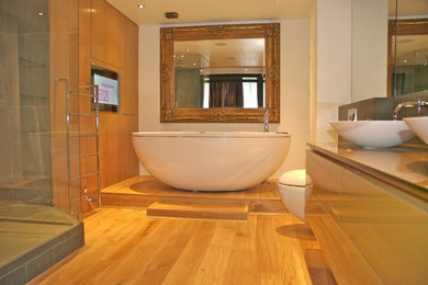 Photo of a modern bathroom in London with a vessel sink, a freestanding bath and a wall mounted toilet.