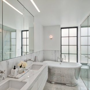 Cette image montre une petit douche en alcôve principale design avec des portes de placard blanches, une baignoire indépendante, un carrelage blanc, un mur blanc, un sol en terrazzo, un lavabo encastré, un plan de toilette en terrazzo, un sol blanc, un plan de toilette blanc, un placard à porte plane et une cabine de douche à porte battante.