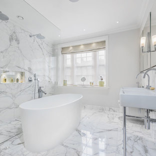 This is an example of a contemporary ensuite bathroom in London with a freestanding bath, a double shower, black and white tiles, grey walls, a console sink and grey floors.