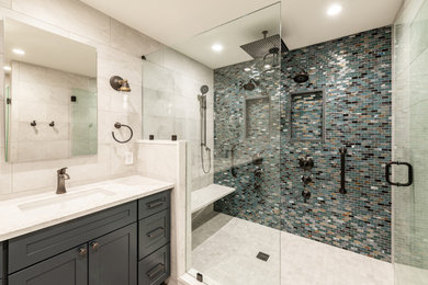 Large transitional master white tile and porcelain tile wood-look tile floor, brown floor, double-sink and wallpaper ceiling bathroom photo in Philadelphia with shaker cabinets, blue cabinets, a one-piece toilet, white walls, an undermount sink, quartzite countertops, a hinged shower door, white countertops and a built-in vanity