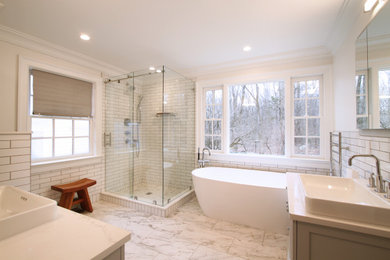 Medium sized traditional ensuite bathroom in New York with shaker cabinets, white cabinets, a freestanding bath, a corner shower, a bidet, white tiles, ceramic tiles, white walls, porcelain flooring, a vessel sink, engineered stone worktops, grey floors, a sliding door, beige worktops, double sinks and a freestanding vanity unit.