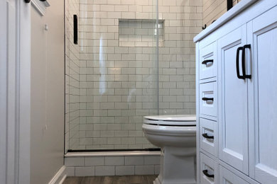 Example of a small classic master porcelain tile and brown floor bathroom design in Bridgeport with furniture-like cabinets, white cabinets, a two-piece toilet, white walls, an undermount sink, quartz countertops and white countertops