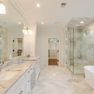 Photo of a transitional master bathroom in Detroit with shaker cabinets, white cabinets, a freestanding tub, an alcove shower, gray tile, metal tile, white walls, marble floors, an undermount sink, marble benchtops, grey floor, a hinged shower door and grey benchtops.