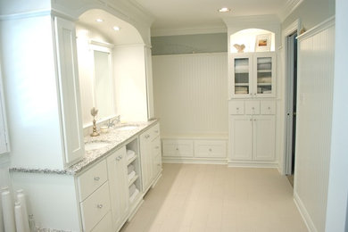 Example of a large beach style ceramic tile drop-in bathtub design in Indianapolis with flat-panel cabinets, white cabinets, blue walls, an undermount sink and granite countertops