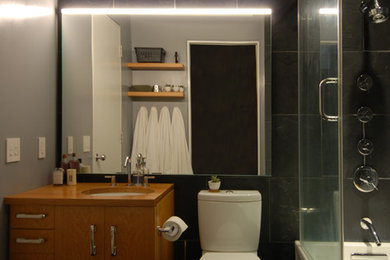 Inspiration for a small contemporary black tile and slate tile slate floor and black floor bathroom remodel in Chicago with flat-panel cabinets, light wood cabinets, a two-piece toilet, black walls, an undermount sink, wood countertops and brown countertops