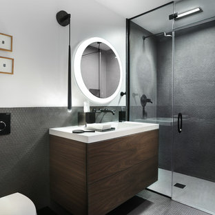 Inspiration for a contemporary 3/4 black tile black floor alcove shower remodel in Chicago with flat-panel cabinets, dark wood cabinets, a wall-mount toilet, gray walls, an integrated sink, a hinged shower door and white countertops