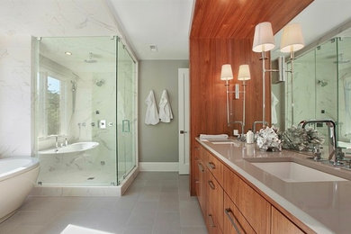 Photo of a contemporary ensuite bathroom in Chicago with flat-panel cabinets, light wood cabinets, a freestanding bath, a corner shower, a two-piece toilet, beige tiles, white tiles, stone slabs, grey walls, ceramic flooring, a submerged sink and marble worktops.