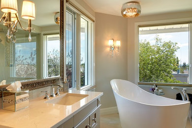 Diseño de cuarto de baño principal tradicional grande con armarios estilo shaker, puertas de armario beige, bañera exenta, baldosas y/o azulejos beige, encimera de granito y encimeras blancas