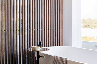 На фото: ванная комната в современном стиле с отдельно стоящей ванной, белыми стенами и коричневым полом