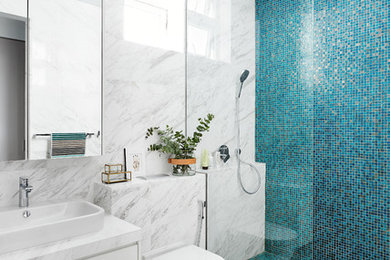 シンガポールにあるコンテンポラリースタイルのおしゃれな浴室 (フラットパネル扉のキャビネット、白いキャビネット、バリアフリー、壁掛け式トイレ、青いタイル、白いタイル、モザイクタイル、大理石の床、ベッセル式洗面器) の写真