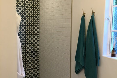 Cette photo montre une douche en alcôve principale tendance avec un carrelage noir et blanc, des carreaux de béton, un mur multicolore, un sol en carrelage de terre cuite, un sol blanc et une cabine de douche à porte battante.