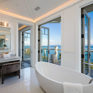 Example of a beach style white floor freestanding bathtub design in Los Angeles with recessed-panel cabinets, white cabinets, white walls and gray countertops