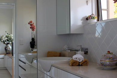 Ejemplo de cuarto de baño contemporáneo con lavabo integrado, puertas de armario blancas, baldosas y/o azulejos blancos, baldosas y/o azulejos de cerámica, paredes blancas y suelo de baldosas de cerámica
