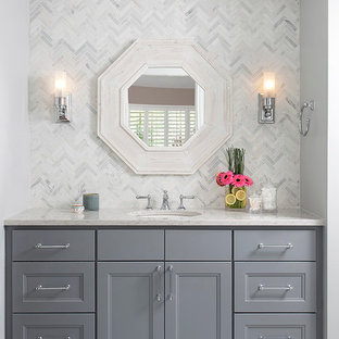 Ispirazione per una piccola stanza da bagno con doccia chic con ante in stile shaker, ante grigie, vasca ad alcova, vasca/doccia, WC monopezzo, piastrelle grigie, piastrelle in pietra, pareti grigie, pavimento in marmo, lavabo sottopiano, top in quarzo composito, pavimento bianco, top bianco e porta doccia a battente