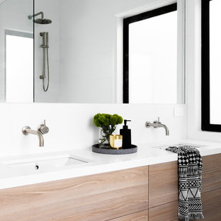 This is an example of a contemporary bathroom in Melbourne with flat-panel cabinets, light wood cabinets, white walls, an undermount sink, black floor and white benchtops.