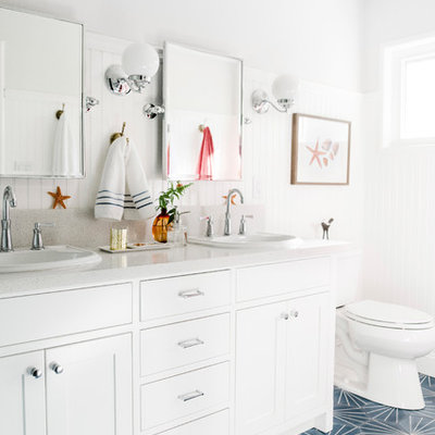 Example of a beach style blue floor bathroom design in Other with shaker cabinets, white cabinets, white walls, a drop-in sink and white countertops