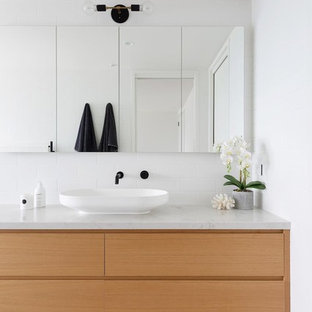 This is an example of a contemporary master bathroom in Sydney with a wall-mount toilet, white tile, subway tile, white walls, ceramic floors, marble benchtops, multi-coloured floor, flat-panel cabinets, a vessel sink, light wood cabinets and multi-coloured benchtops.