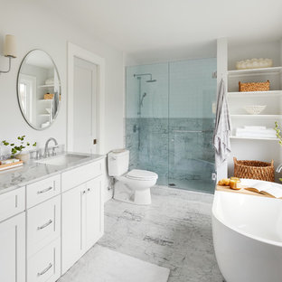 Inspiration for a mid-sized transitional master gray tile, white tile and marble tile marble floor and gray floor bathroom remodel in Chicago with shaker cabinets, white cabinets, a two-piece toilet, gray walls, an undermount sink, marble countertops, a hinged shower door and white countertops