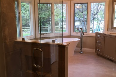 Example of a large trendy master porcelain tile and beige floor bathroom design in Detroit with shaker cabinets, an undermount sink, quartzite countertops, brown cabinets, beige walls and a hinged shower door