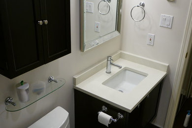 Example of a mid-sized trendy beige tile, black and white tile, brown tile, gray tile and porcelain tile porcelain tile and gray floor bathroom design in Vancouver with shaker cabinets, dark wood cabinets, white walls, an undermount sink, solid surface countertops and a one-piece toilet