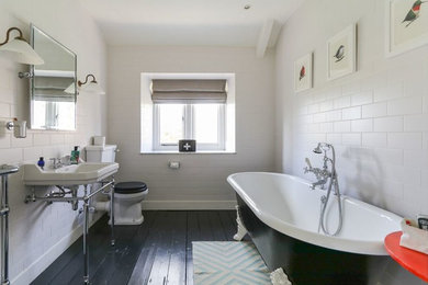 Inspiration for a large traditional family bathroom in Other with a claw-foot bath, a shower/bath combination, a two-piece toilet, white tiles, ceramic tiles, white walls, dark hardwood flooring, a console sink and black floors.