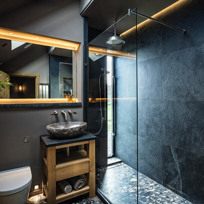 Inspiration for a coastal 3/4 black tile bathroom remodel in Cheshire with open cabinets, light wood cabinets, a wall-mount toilet, black walls and a vessel sink