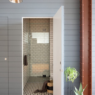 This is an example of a small contemporary bathroom in Melbourne with an alcove shower, a one-piece toilet, white tile, ceramic tile, white walls, mosaic tile floors, black floor and a hinged shower door.