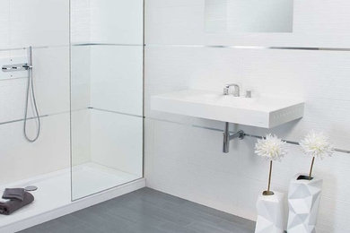 Example of a mid-sized 3/4 white tile and porcelain tile laminate floor and gray floor alcove shower design in New York with white walls, a wall-mount sink, quartz countertops and a hinged shower door