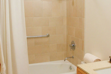ポートランドにあるアジアンスタイルのおしゃれな浴室 (アンダーカウンター洗面器、フラットパネル扉のキャビネット、中間色木目調キャビネット、珪岩の洗面台、一体型トイレ	、ベージュのタイル、石タイル、シャワー付き浴槽	) の写真
