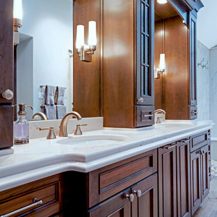 Großes Klassisches Badezimmer En Suite mit flächenbündigen Schrankfronten, hellbraunen Holzschränken, Eckbadewanne, offener Dusche, Wandtoilette mit Spülkasten, grauen Fliesen, Steinplatten, beiger Wandfarbe, Porzellan-Bodenfliesen, Unterbauwaschbecken, Quarzwerkstein-Waschtisch, beigem Boden, offener Dusche und weißer Waschtischplatte in Philadelphia