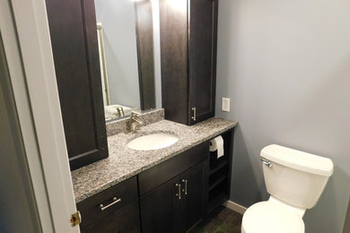 Example of a small porcelain tile bathroom design in Columbus with shaker cabinets, dark wood cabinets, a two-piece toilet, an undermount sink and granite countertops