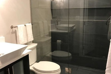 Inspiration for a small modern master gray tile and ceramic tile ceramic tile and gray floor walk-in shower remodel in Portland with glass-front cabinets, dark wood cabinets, a two-piece toilet, beige walls, a vessel sink, quartz countertops, a hinged shower door and white countertops