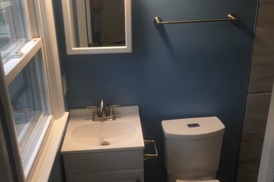 Photo of a small eclectic shower room bathroom in Other with shaker cabinets, white cabinets, an alcove shower, a two-piece toilet, grey tiles, porcelain tiles, blue walls, porcelain flooring, an integrated sink, solid surface worktops, grey floors, a shower curtain and white worktops.