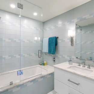 Esempio di una stanza da bagno contemporanea con ante lisce, ante bianche, vasca ad alcova, vasca/doccia, piastrelle blu, piastrelle di vetro, lavabo sottopiano, doccia aperta, top bianco, un lavabo e mobile bagno sospeso