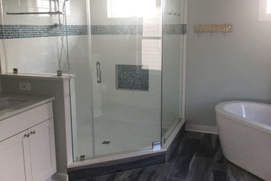 Modern inredning av ett mellanstort en-suite badrum, med skåp i shakerstil, ett fristående badkar, en hörndusch, en toalettstol med hel cisternkåpa, blå kakel, vit kakel, keramikplattor, klinkergolv i porslin, ett undermonterad handfat, granitbänkskiva, dusch med gångjärnsdörr, vita skåp, grå väggar och brunt golv