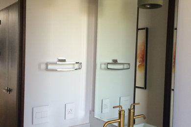 Modelo de cuarto de baño minimalista de tamaño medio con armarios con paneles lisos, puertas de armario de madera en tonos medios, paredes blancas, suelo de madera en tonos medios, aseo y ducha, lavabo encastrado, encimera de mármol y suelo marrón