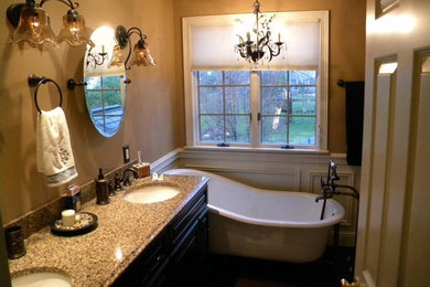 Freestanding bathtub - mid-sized traditional 3/4 medium tone wood floor freestanding bathtub idea in Other with shaker cabinets, dark wood cabinets, brown walls, an undermount sink and granite countertops